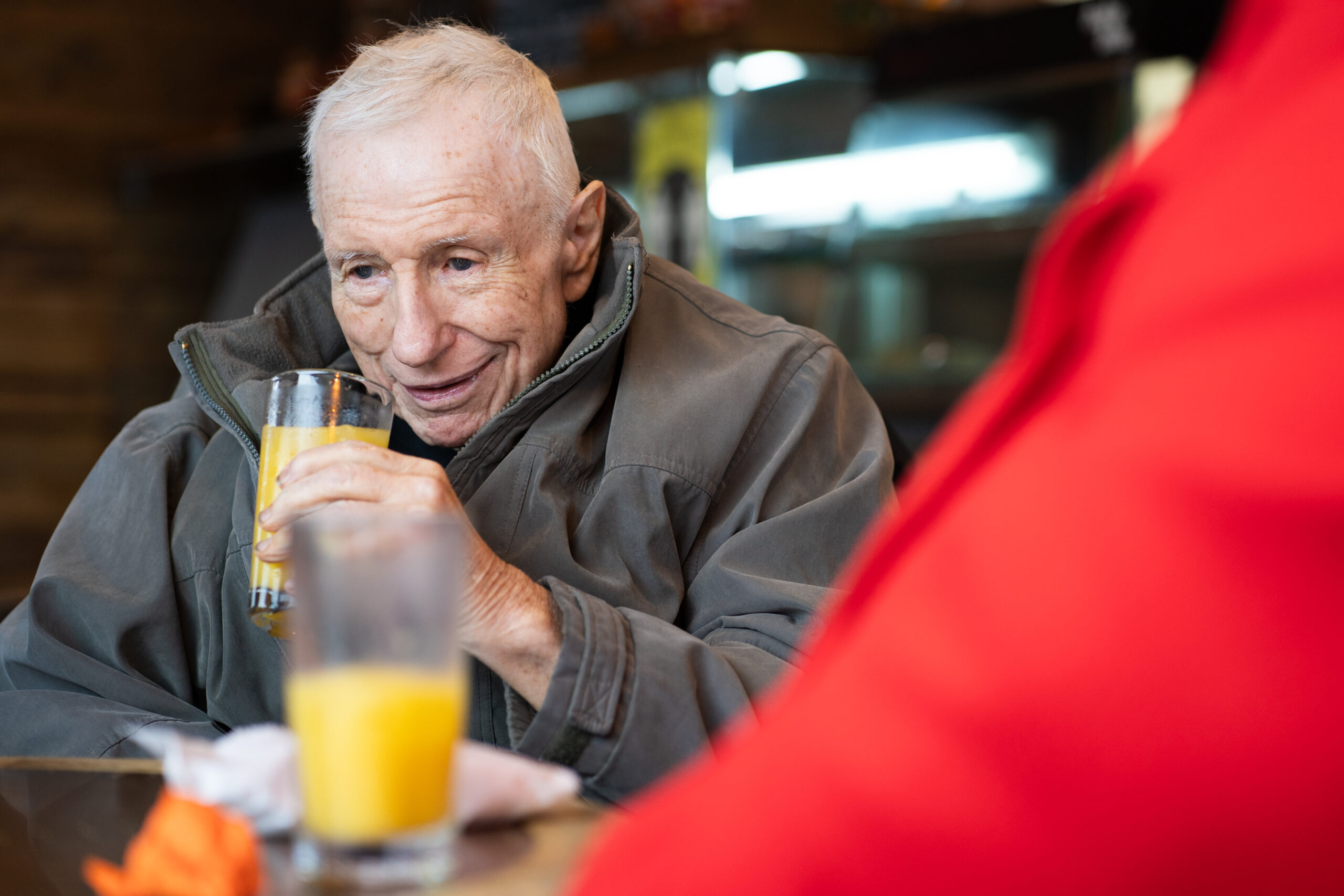 Respite care - Elderly gentleman in a grey coat holding a glass of orange juice